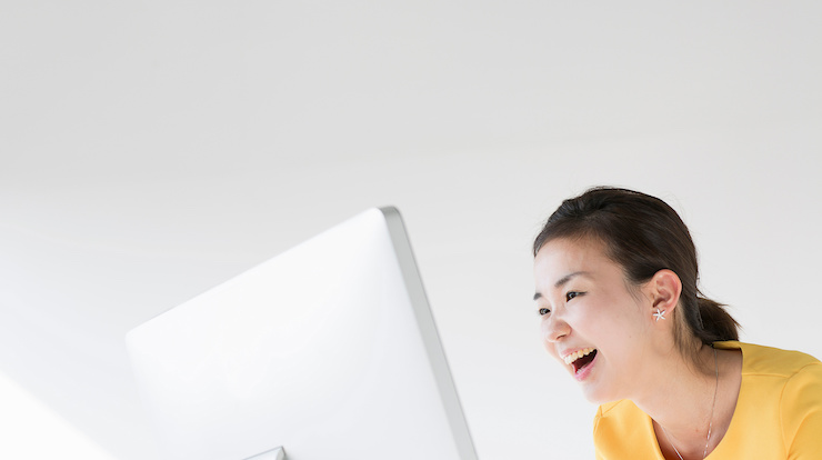 笑顔でパソコンの画面を見ている女性