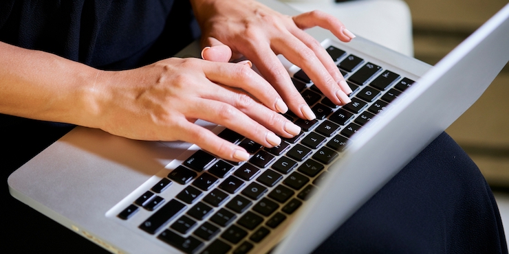 ノートパソコンでタイピングをしている女性の手元