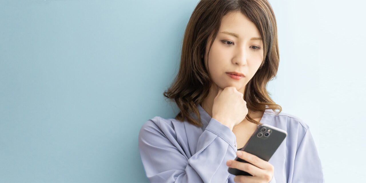 スマートフォンを見て悩んでいる女性