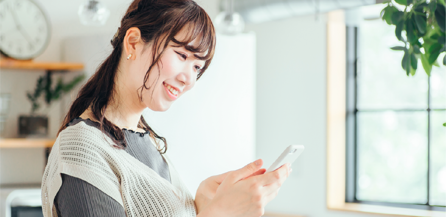 スマホの画面を見て笑っている女性