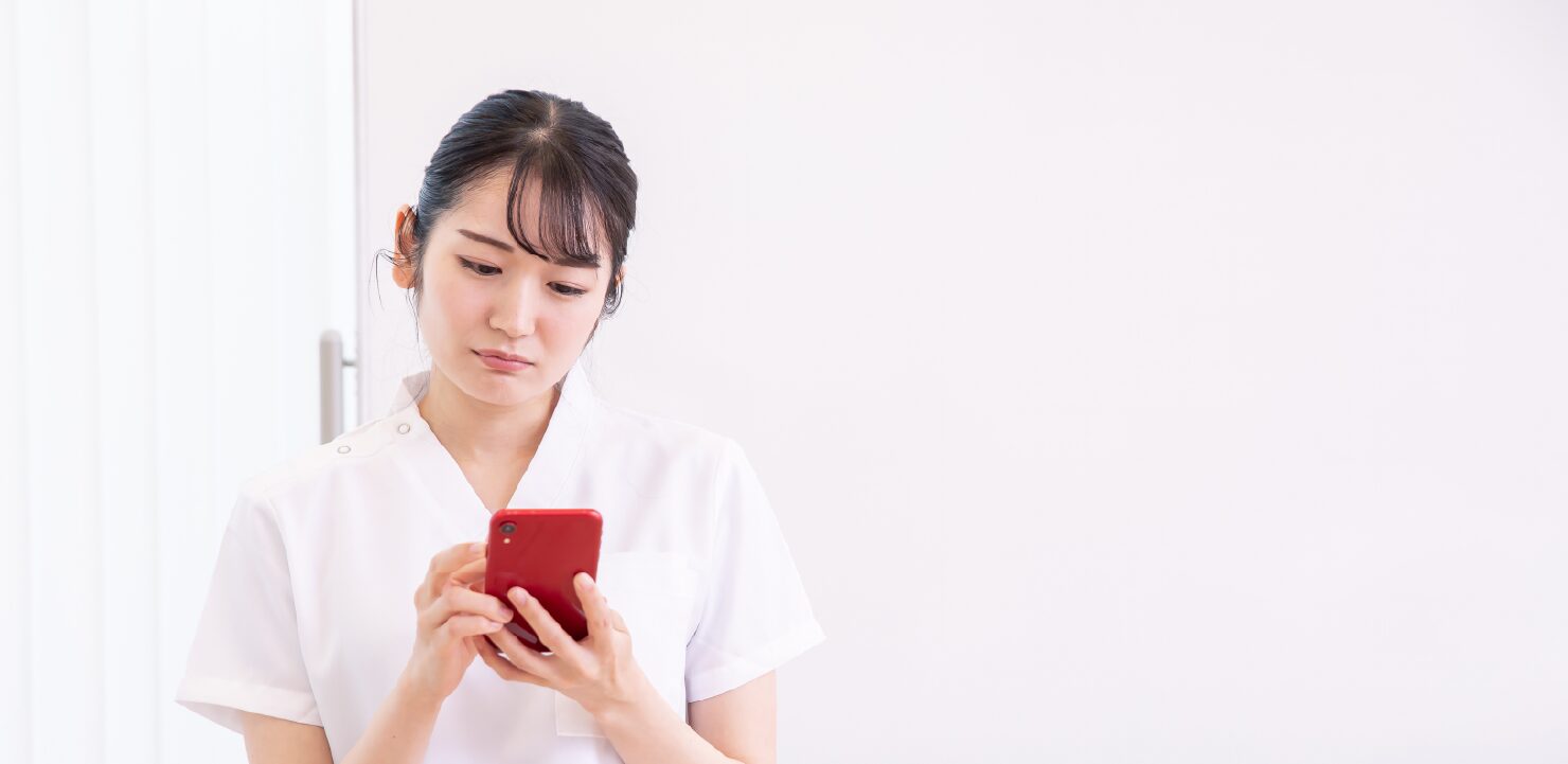 スマホを見て困っているエステサロンスタッフ