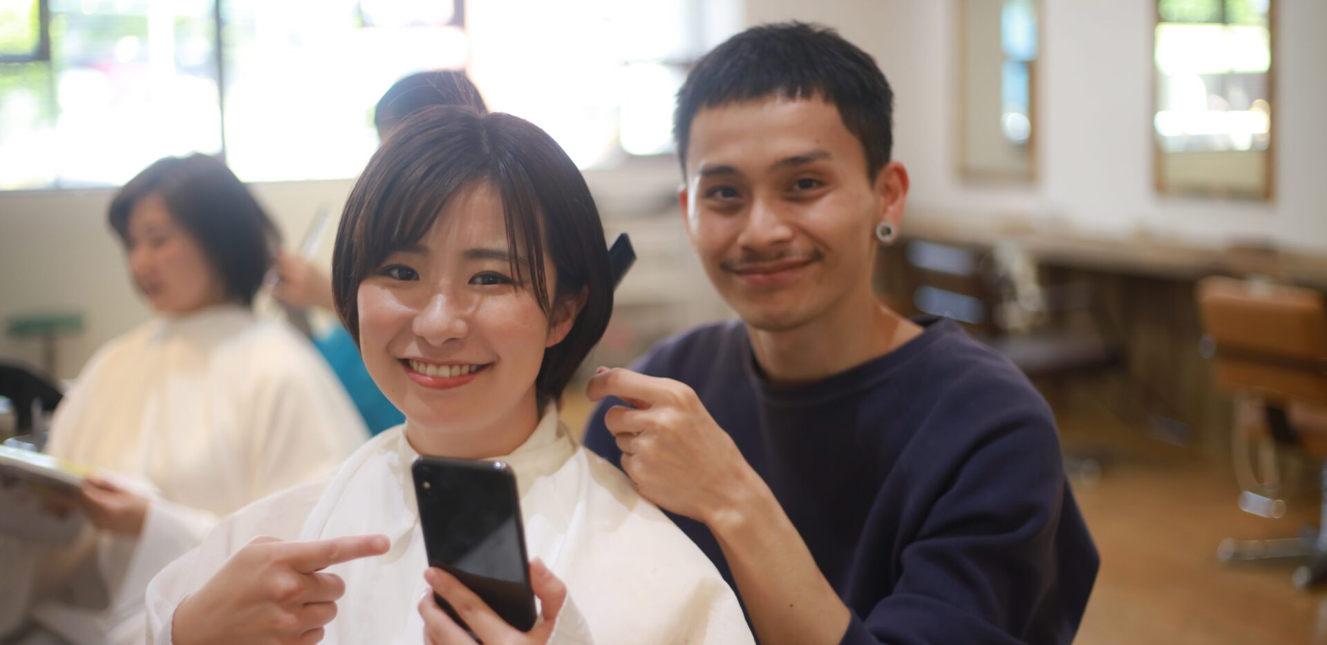 美容師の男性とスマホを持っている女性客