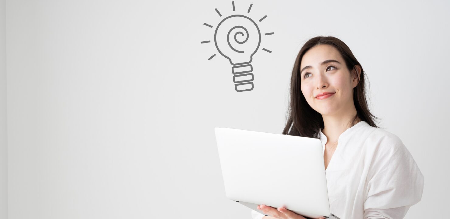 ノートPCを持ちながらアイデアが思い浮かんでいる女性