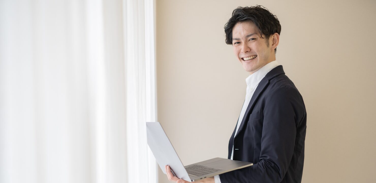 ノートPCを持っているスーツ姿の男性