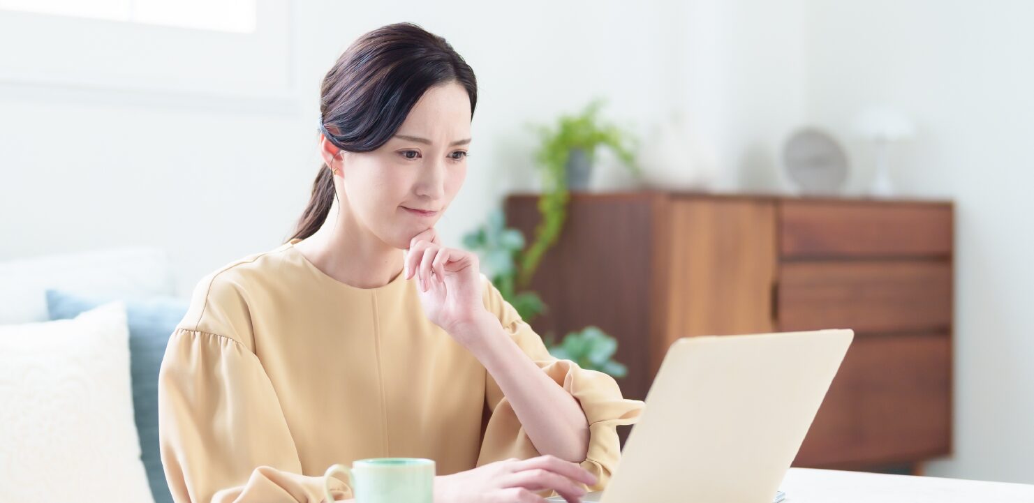 PCの画面を見ながら悩んでいる女性