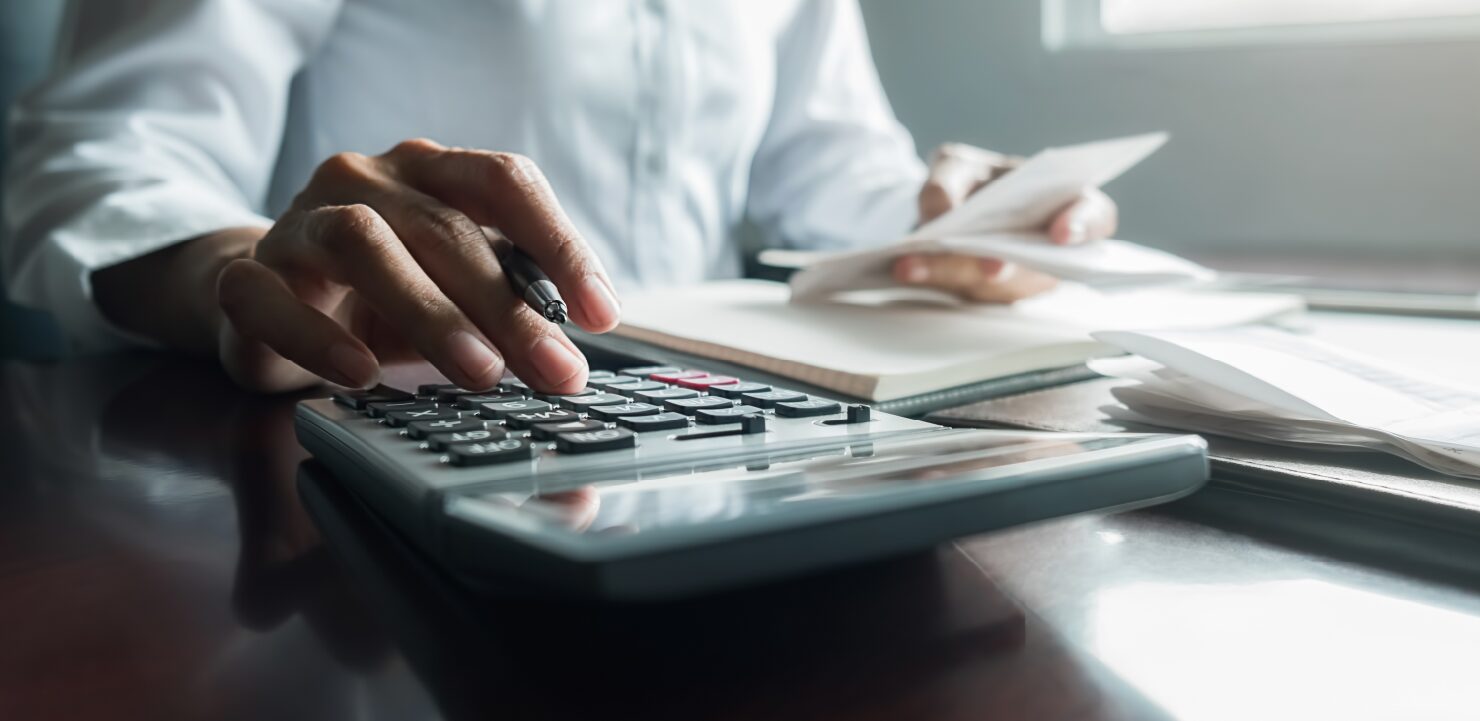 電卓を使用して記帳している男性の手元