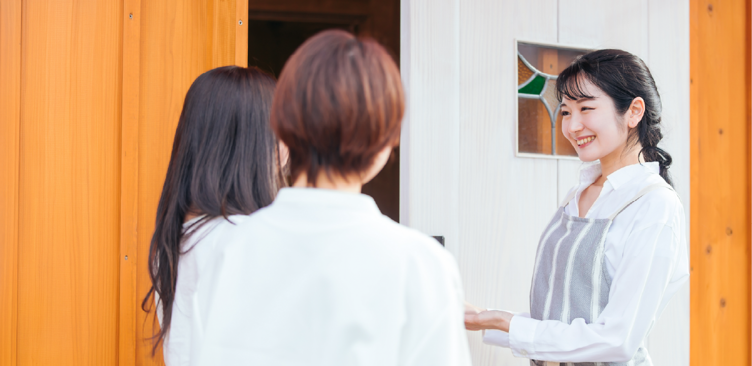 店の入口で客を迎える女性店員