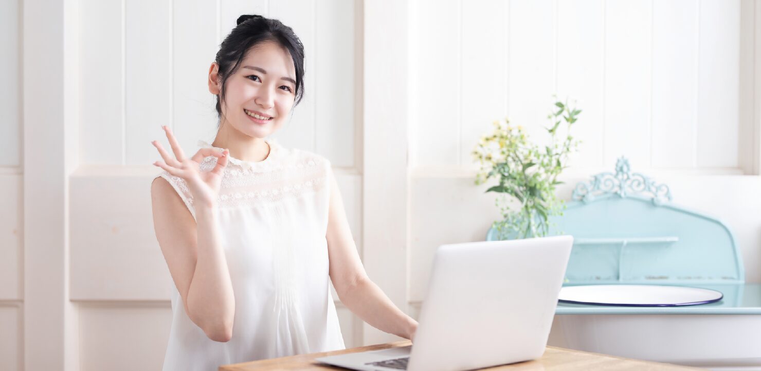 OKサインをしているPCを使っている女性