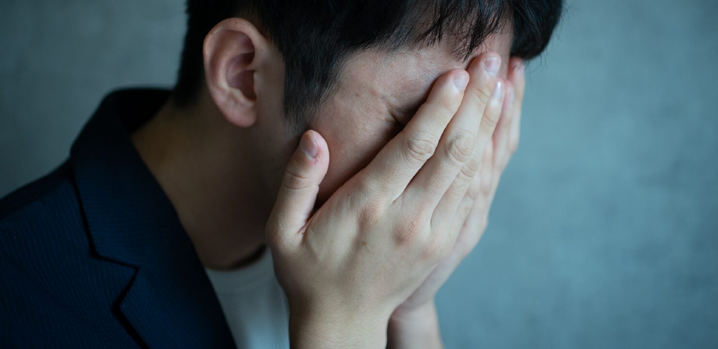 頭を手で覆っている男性